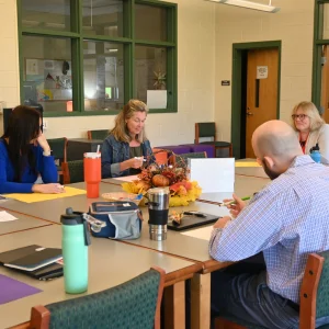 Faculty gathered at a table and having a discussion.