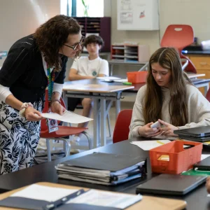 Teacher holding a paper while helping student with an assignment.