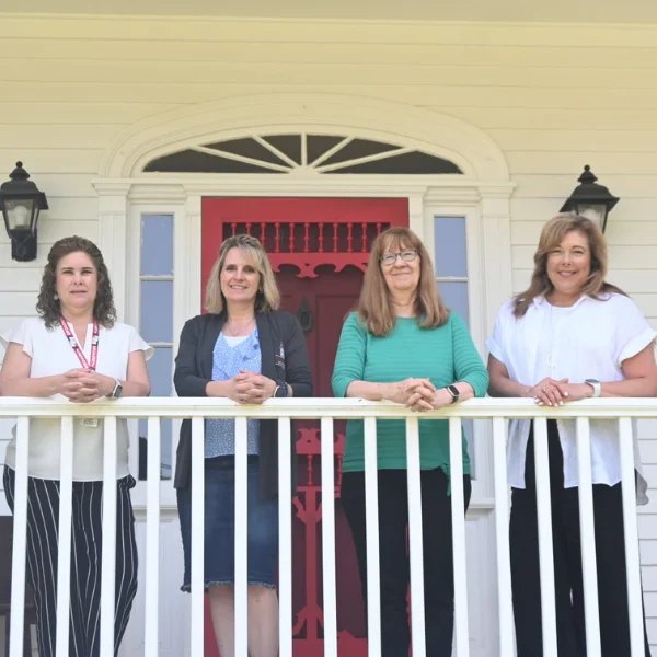 Four staff members smiling on a porch.