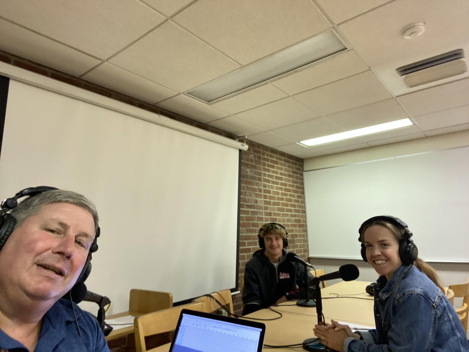 Mr. Konstant, Jacob Albert, and Mrs. Bernard sit at a podcast table. 