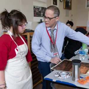 Teacher assisting student with art project.